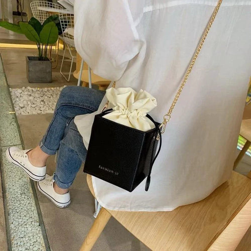 Mandotos chic alligator pattern bucket bag with adjustable shoulder strap and gold-tone hardware on a white background.