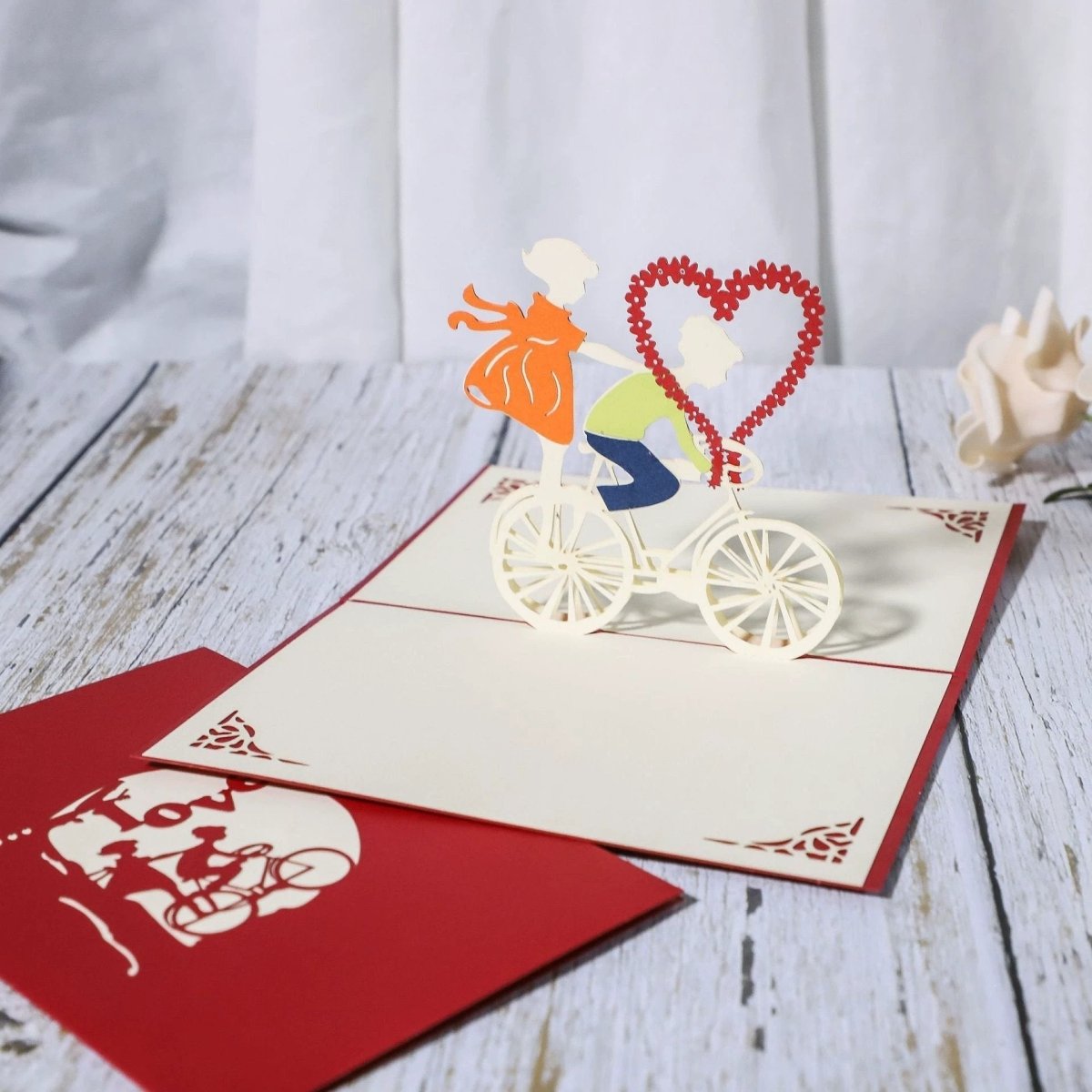 3D laser-cut engagement card by MANDOTOS featuring a red heart and romantic silhouette design.