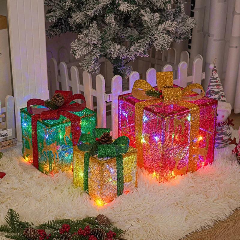 Lighted Christmas gift box outdoor decoration by MANDOTOS with a festive bow, illuminated for holiday outdoor display.