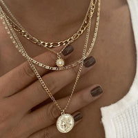 Mandotos chunky gold layered necklace with coin pendant and sun charm for women, featuring multiple chain styles and intricate details.