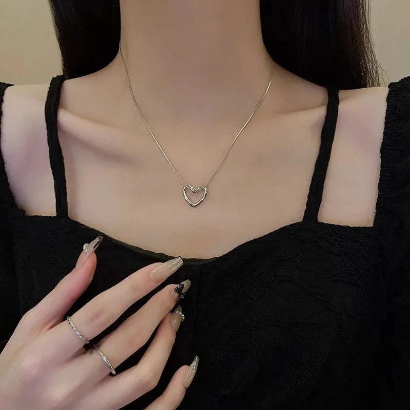 Stainless steel twist hollow heart necklace on a clavicle chain, featuring a sleek and modern design by MANDOTOS.