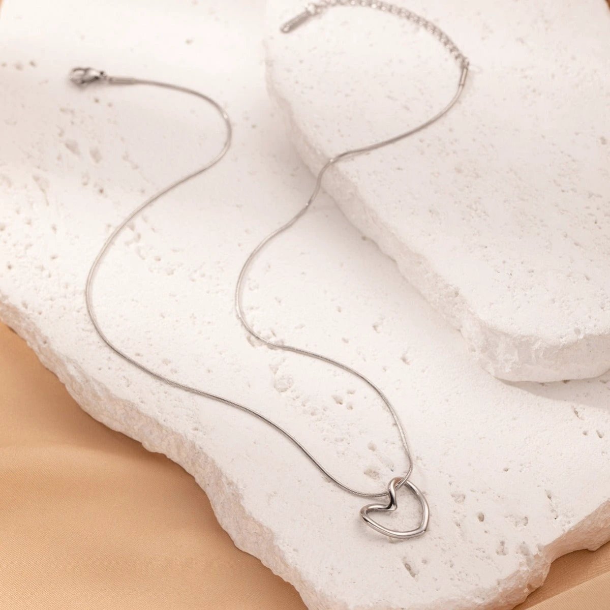 Stainless steel twist hollow heart necklace with clavicle chain by MANDOTOS, close-up view of the elegant jewelry piece.