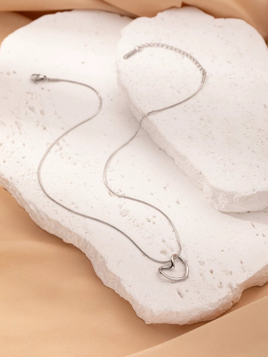 Stainless steel twist hollow heart necklace on a clavicle chain, featuring a modern design by MANDOTOS.