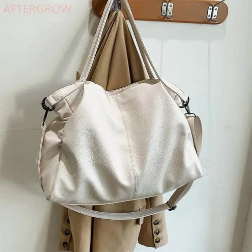 Elegant leather carryall bag by MANDOTOS featuring a sleek design with sturdy handles and a spacious interior.