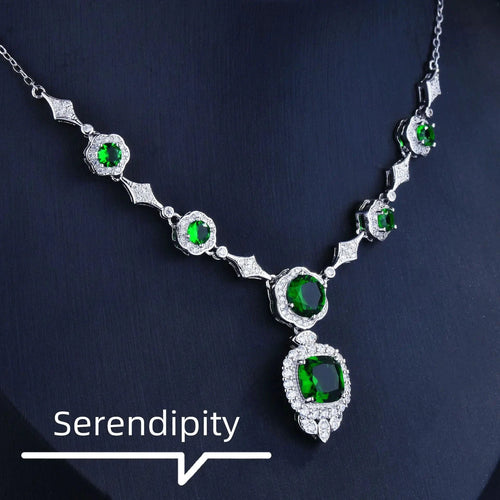 Mandotos Emerald Elegance white gold necklace with a central emerald gemstone and intricate gold detailing.