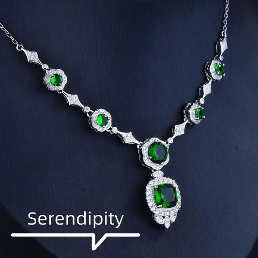 Mandotos Emerald Elegance white gold necklace with a central emerald gemstone and intricate gold detailing.