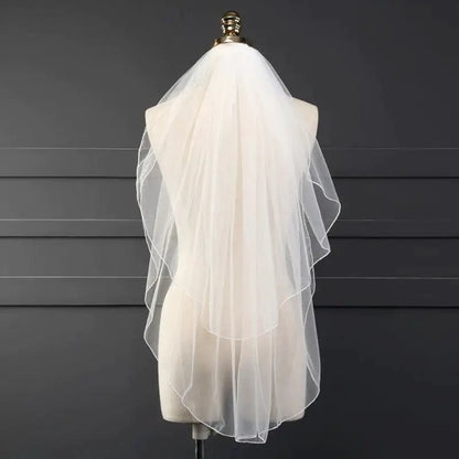 Ethereal double-tiered veil by MANDOTOS featuring delicate lace and soft tulle layers for a graceful bridal look.