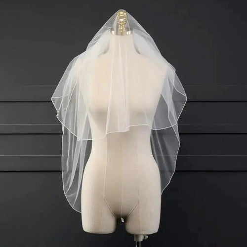 Ethereal double-tiered veil by MANDOTOS, sheer fabric with delicate lace edges, perfect for wedding or bridal occasion.