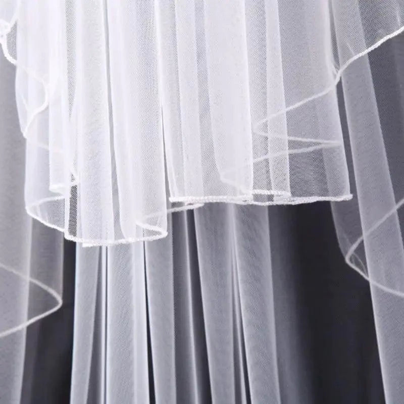 Ethereal double-tiered veil by MANDOTOS featuring delicate lace and flowing tulle for a romantic bridal look.