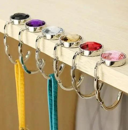 Mandotos foldable metal purse hook, portable handbag hanger with compact design for holding bags on tables or counters.