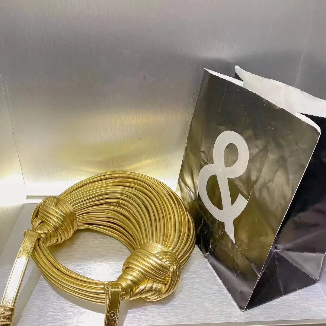 Luxury MANDOTOS women's handbag, gold handwoven noodle design with rope knot details, silver evening clutch for elegant occasions.