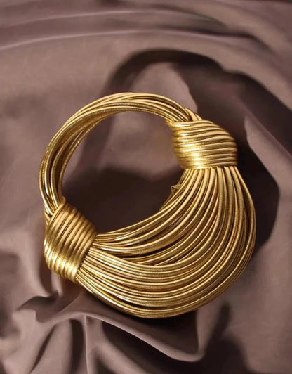 Mandotos luxury women's handbag in gold with handwoven noodle design, rope knot details, and silver evening clutch style.