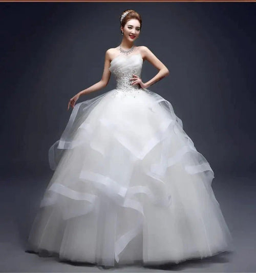 Elegant one-shoulder bridal gown by MANDOTOS INTERNATIONAL featuring intricate lace and flowing fabric for a sophisticated wedding look.