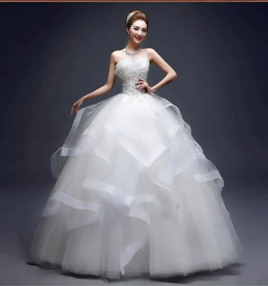 Elegant one-shoulder bridal gown by MANDOTOS INTERNATIONAL featuring intricate lace and flowing fabric for a sophisticated wedding look.