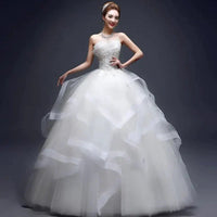 Elegant one-shoulder bridal gown by MANDOTOS INTERNATIONAL featuring lace details and flowing train.