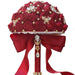 Dark red Eternal Rose bridal bouquet by MANDOTOS INTERNATIONAL, featuring preserved roses arranged in a romantic floral display.