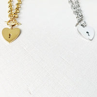 Heart-shaped key toggle necklace by MANDOTOS INTERNATIONAL featuring a silver chain and a detailed heart-shaped key pendant.