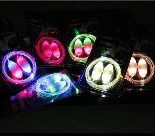LED Light-Up Shoelaces by MANDOTOS glow in the dark, shown laced through sneakers with illuminated tips in a close-up shot.