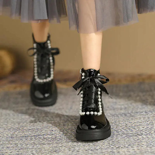Mandotos patent leather ankle boots with sleek design and pointed toe, featuring a shiny finish and low block heel.