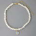 Mandotos round medal pearl necklace with irregular pearls, elegant jewelry piece showcasing a sophisticated design and natural pearl texture.