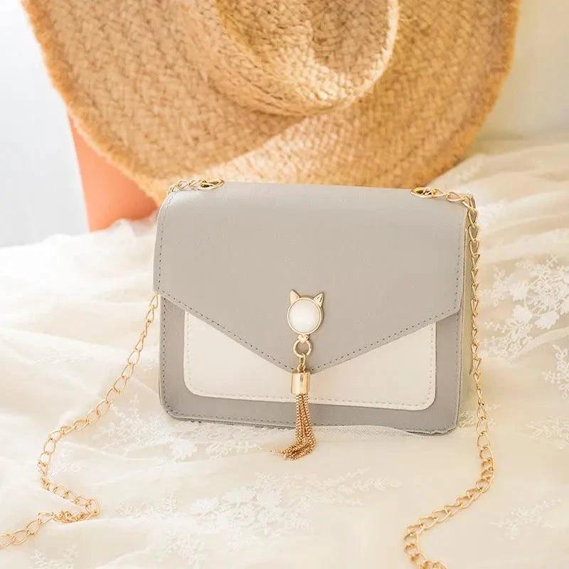 Mandotos small women's crossbody bag with cat lock chain detail, messenger style, black leather design with adjustable strap.