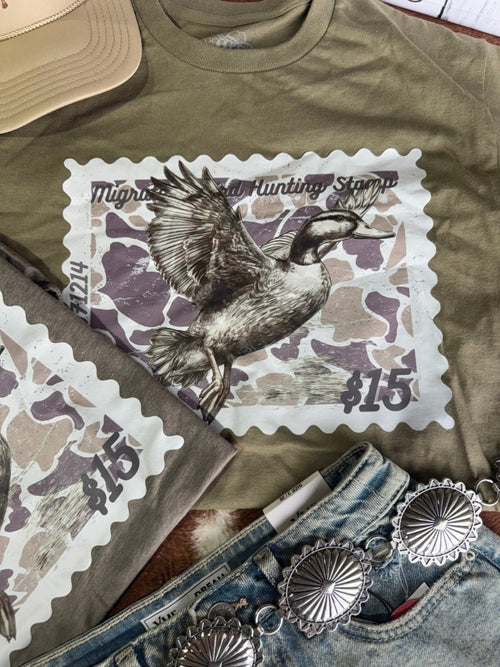 Olive green Duck Stamp graphic tee by Wild Junkie featuring a detailed duck stamp design on a casual men's graphic T-shirt.